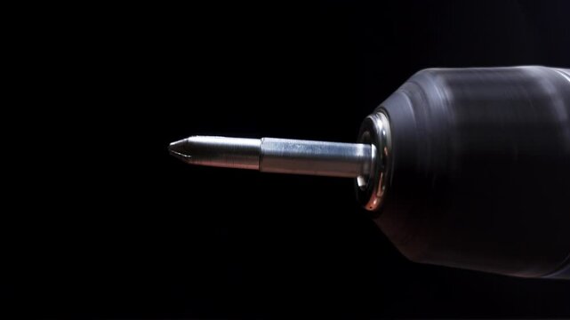 Macro view of spinning screwdriver bit on power drill. Close up view of specialized screw tip. Construction concept.