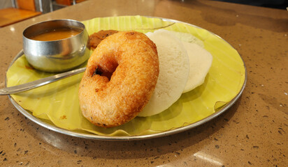 A Picture of an Indian cuisine 'Rice Idly and Vada' served with Sambar and masala chutney is a...