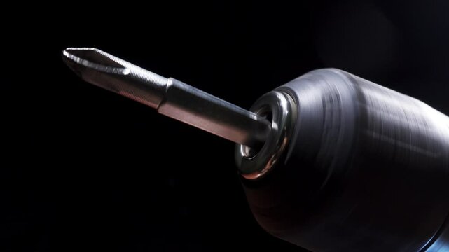 Macro view of a specialized screw tip, showing a spinning screwdriver bit attached to a power drill in action. Construction concept.