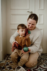 Grandmother and grandson in beige knitted sweaters look at vintage Christmas balls. Preparation for Christmas