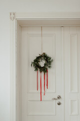 Rustic Christmas wreath on a white door. Preparing for a merry Christmas and New Year 2025