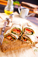 Sliced sandwich tortilla with tomatoes , salad , cream cheese and ham .