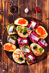 Cocktail canapes with herring, cream cheese and caviar on rye bread