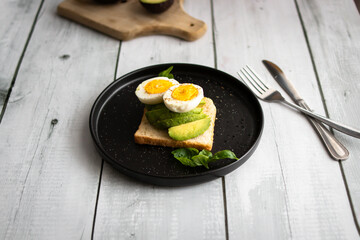 
Sandwiches with avocado, tomatoes and poached eggs. on a wooden backyard. Snidanok.