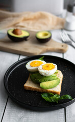 
Sandwiches with avocado, tomatoes and poached eggs. on a wooden backyard. Snidanok.