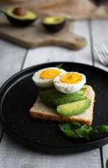 
Sandwiches with avocado, tomatoes and poached eggs. on a wooden backyard. Snidanok.