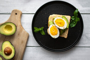 
Sandwiches with avocado, tomatoes and poached eggs. on a wooden backyard. Snidanok.