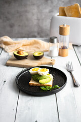 
Sandwiches with avocado, tomatoes and poached eggs. on a wooden backyard. Snidanok.