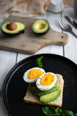 
Sandwiches with avocado, tomatoes and poached eggs. on a wooden backyard. Snidanok.