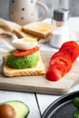 
Sandwiches with avocado, tomatoes and poached eggs. on a wooden backyard. Snidanok.