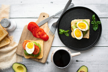 
Sandwiches with avocado, tomatoes and poached eggs. on a wooden backyard. Snidanok.