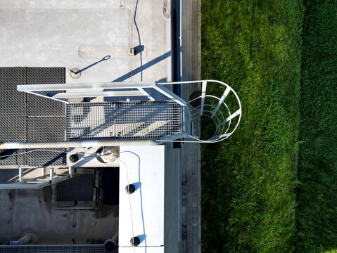 the fire ladder leading to the roof of the hall is secured by a grille protective railing. white metal warehouse walls. galvanized iron and a pipe for connecting fire hose, lightning rod