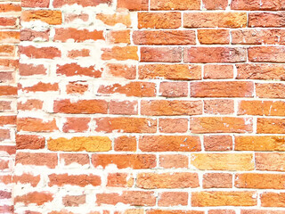 Red brick wall with uneven texture and faded mortar, showing signs of wear and natural weathering