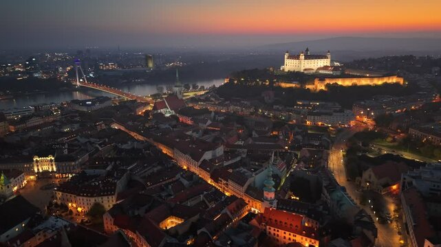 Stunning twilight view of Bratislava with the illuminated castle and cityscape along the Danube River at sunset. Aerial evening view. Evening illuminated Bratislava old city, Slovakia