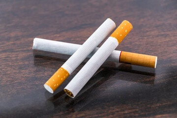 Three cigarettes on the wooden table.