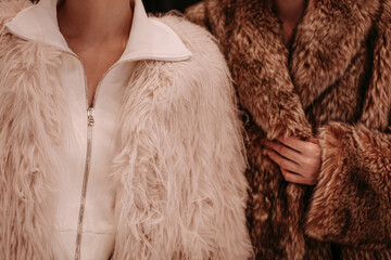 Close up winter white and brown fur coats on women's figures, warm luxury clothing