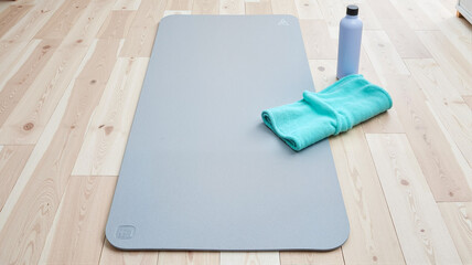 Yoga mat, bottle, and towel on wooden floor