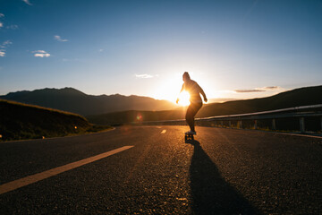Skateboarder skateboarding on the sunset mountain top road