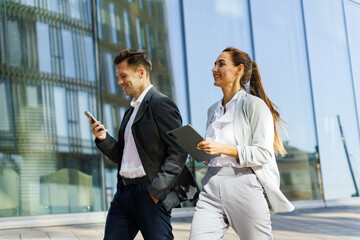 Professionals Walking Confidently in a Modern Urban Setting While Engaging With Digital Devices