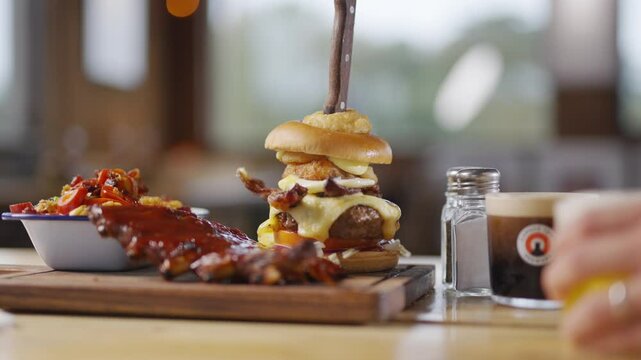 Portrait shot of the combo burger dish of a restaurant with some bacons served on a wooden plate
