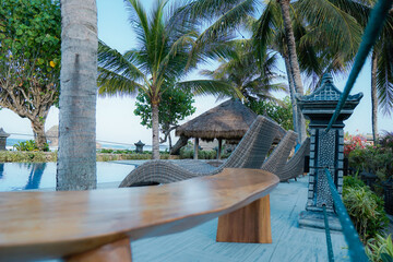 Sunchairs at the swimming pool.Relaxing in swimming pool at spa resort.Beach chairs under coconut palm near the sea vacation concept
