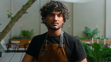 Happy joyful Latino American ethnic man male smiling cafe worker in apron guy waiter cleaner barista portrait small business owner employee looking at camera smile outside town. Employment street food