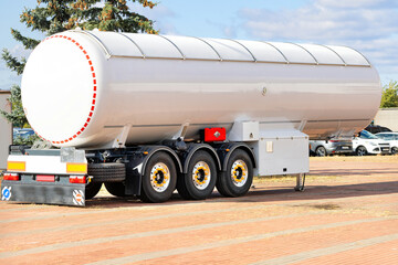 A striking white fuel tanker parked under a clear blue sky in an industrial area during the day