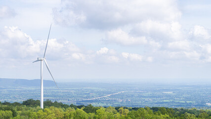 A wind turbine stands alone on a mountain in front of the highlands of Thailand. For producing...