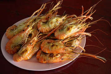 Several grilled shrimps on a pink plate placed on the table.