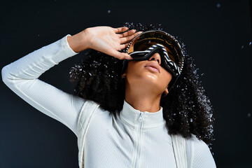 A stunning brunette woman models a chic ski suit while striking a fashionable pose indoors.