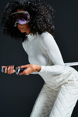 A beautiful brunette woman in a chic ski suit poses confidently in a studio, highlighting winter fashion trends.