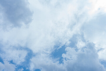Fluffy white clouds drift across a vast expanse of clear blue sky
