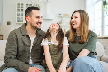 Happy family at home. Mother father children daughter relaxing on sofa indoor. Mom dad parents kid girl relax playing hugging having fun together. Family smiling laughing enjoying tender moment