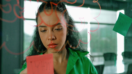 Young hispanic employee writing on colorful sticky notes. Smart businesswoman sharing marketing...