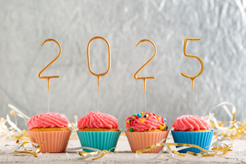 Christmas greeting card with cupcakes and gold sparklers numbers 2025. Holiday muffins with pink...