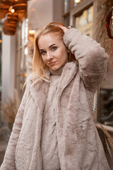Portrait of blond attractive woman in a fur coat outdoor. City street. Christmas mood. Holiday weekend. Vertical frame