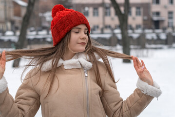 Portrait of a beautiful girl in a red hat and coat on the street in winter