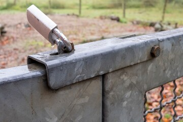 Secure metal gate closed with padlock in wet rural area