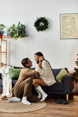 The couple enjoys a tender embrace on their cozy couch decorated for Christmas.