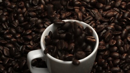 Close up of coffee bean falling in to coffee cup surrounded by pile of beans. Dropping aromatic blending bean in to white cup. Top view of coffee drop in to glass with black background. Comestible.