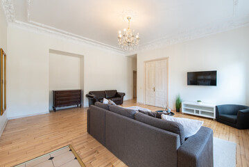 Modern Retro, Classic Style Home Living Room Interior with Open TV Area and TV Screen, Desk, Sofa, And Coffee Table. Flowers, Windows and Curtains in Background. Hardwood Floor,