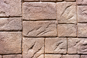 The stone wall is patterned in light brown tones, each cube is different, small and large alternately.