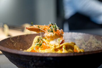 Spaghetti Carbonara pasta Egg and Cheese creamy cream sauce with Shrimp and micro herb decoration on the top of it of earthware circle bowl in studio light.