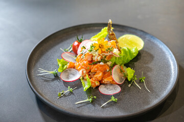 Spicy Raw Salmon Salad Thai food style decorated with Crispy fried fish skin and Yellow Flower on top and micro herb around dish. Ready to serve and eat.