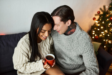 A joyful couple shares tender moments at home, sipping drinks and enjoying the festive spirit.