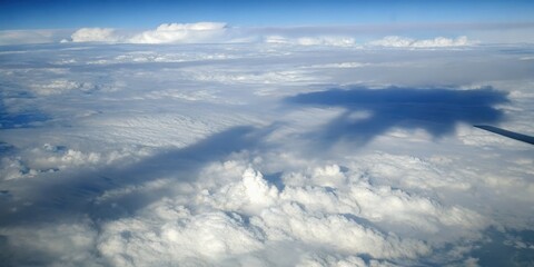 Aerial view of fluffy white clouds from an airplane window with a blue sky