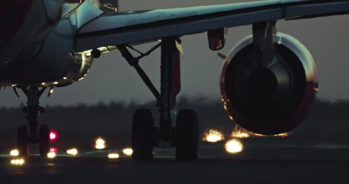 Nighttime Close-Up of Aircraft Wheels Rolling on Lit Runway Showing Airport Life and Passenger Air Travel. High quality 4k footage