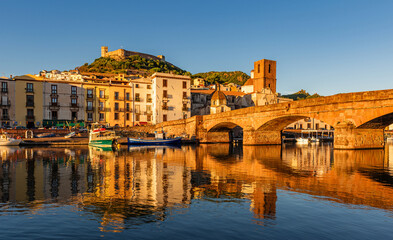 Panoramic view of the picturesque town of Bosa with its colorful houses reflected in the Temo River at golden hour. Sardinia, Italy.
