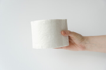 Close-up of a woman hand with toilet paper isolated on a white background. Hand holding roll of tissue paper. white roll toilet paper on female hand