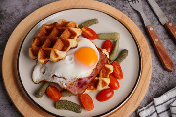 Breakfast waffles with fried eggs Tomatoes and pickled cucumbers In a white plate with a black background
